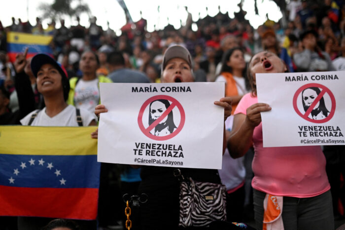 Supporters of Venezuelan President Nicolas Maduro hold signs rejecting opposition leader Maria Corina Machado during a rally at Miraflores Palace following the presidential election in Caracas, Venezuela. 