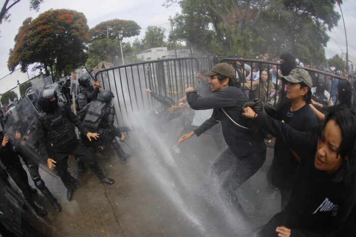 Los manifestantes marcharon pacíficamente desde la glorieta Minerva, pero al encontrar la zona cercada quitaron las vallas y se fueron acercando a Casa Jalisco, donde policías antimotines les recibieron con amenazas y violencia física.